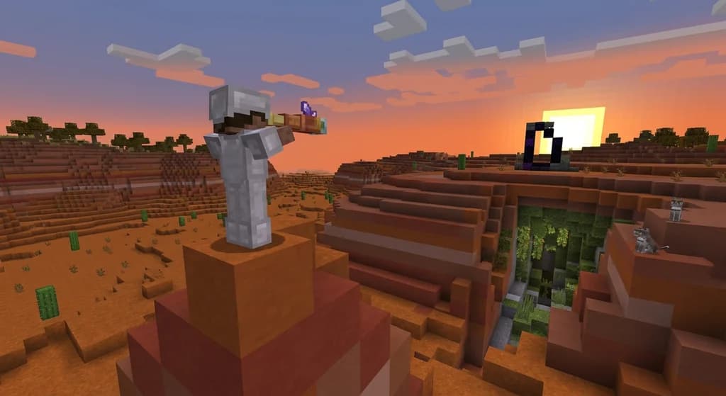 A player character in iron armor uses a spyglass to scout a badlands biome from a high hoodoo, overlooking a ruined portal and a lush cave entrance at sunset.